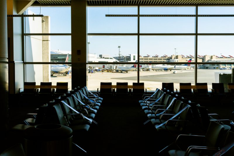 Traveller with a small bag looking out over an airport apron